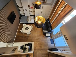 Una sala de estar moderna con un sofá, una mesa de comedor y una zona de cocina con encimera y armarios.