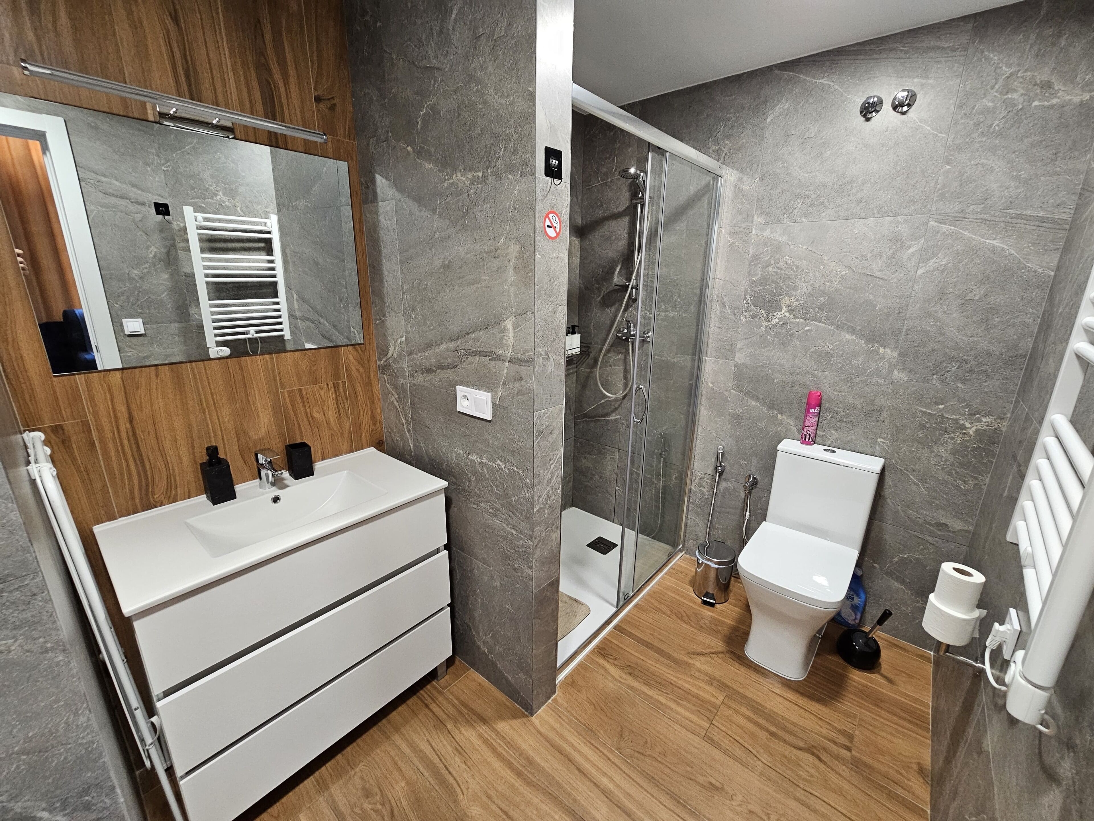 A modern bathroom with a white vanity, a glass-enclosed shower, and a toilet.