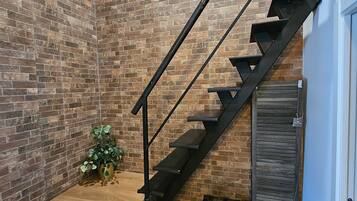 Una escalera con un muro de ladrillo, una planta pequeña y un baúl antiguo.
