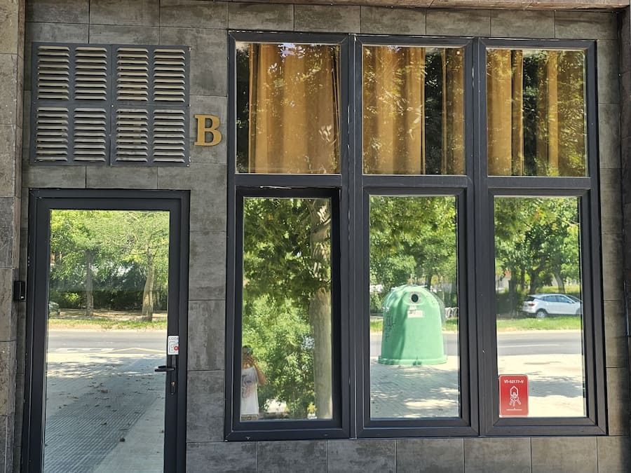 Facciata di un edificio con un'ampia finestra, un ingresso e un sistema di ventilazione.