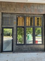 Fachada de edificio con un ventanal grande, una puerta y una unidad de ventilación.