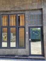 Fachada de un edificio con ventanas amplias, una puerta y un sistema de ventilación.