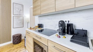 Una cocina moderna con armarios de madera, encimera de mármol, cocina por inducción negra, cafetera y tostadora.