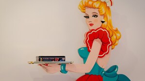 A stylized illustration of a person holding a tray with a game console. - Setubal Boutique Apartment IV by Homing (Setubal)