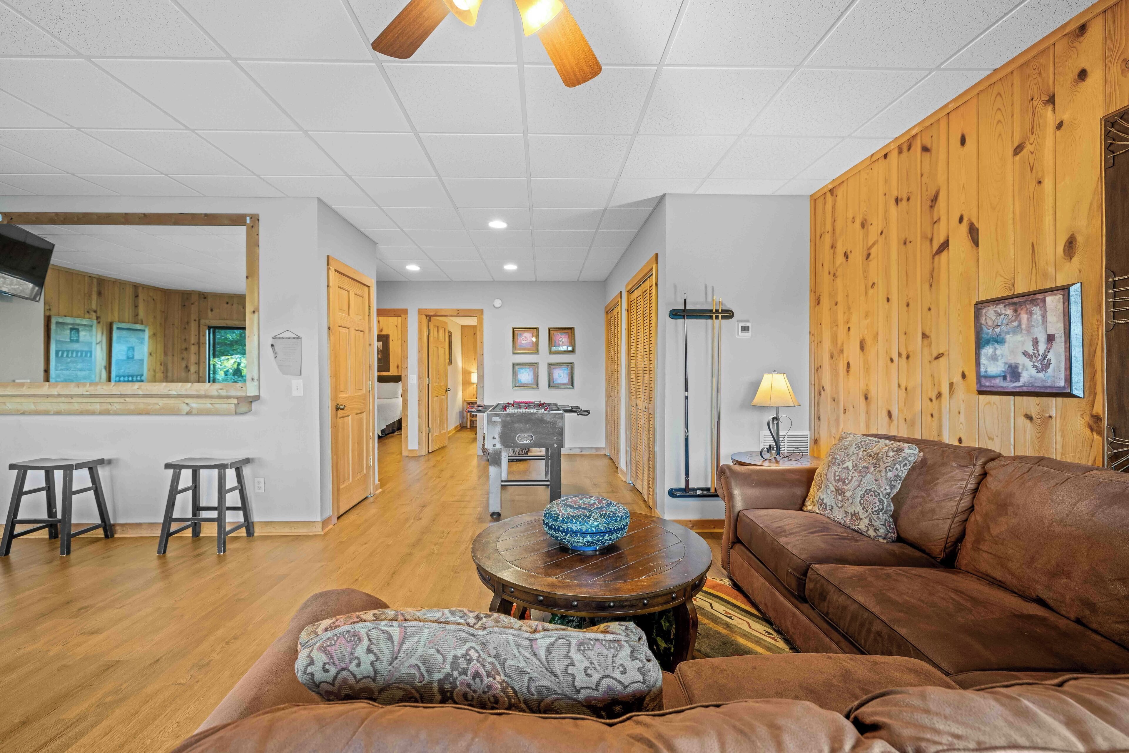 A spacious living area with a brown leather sofa, a round coffee table, and a wooden accent wall.