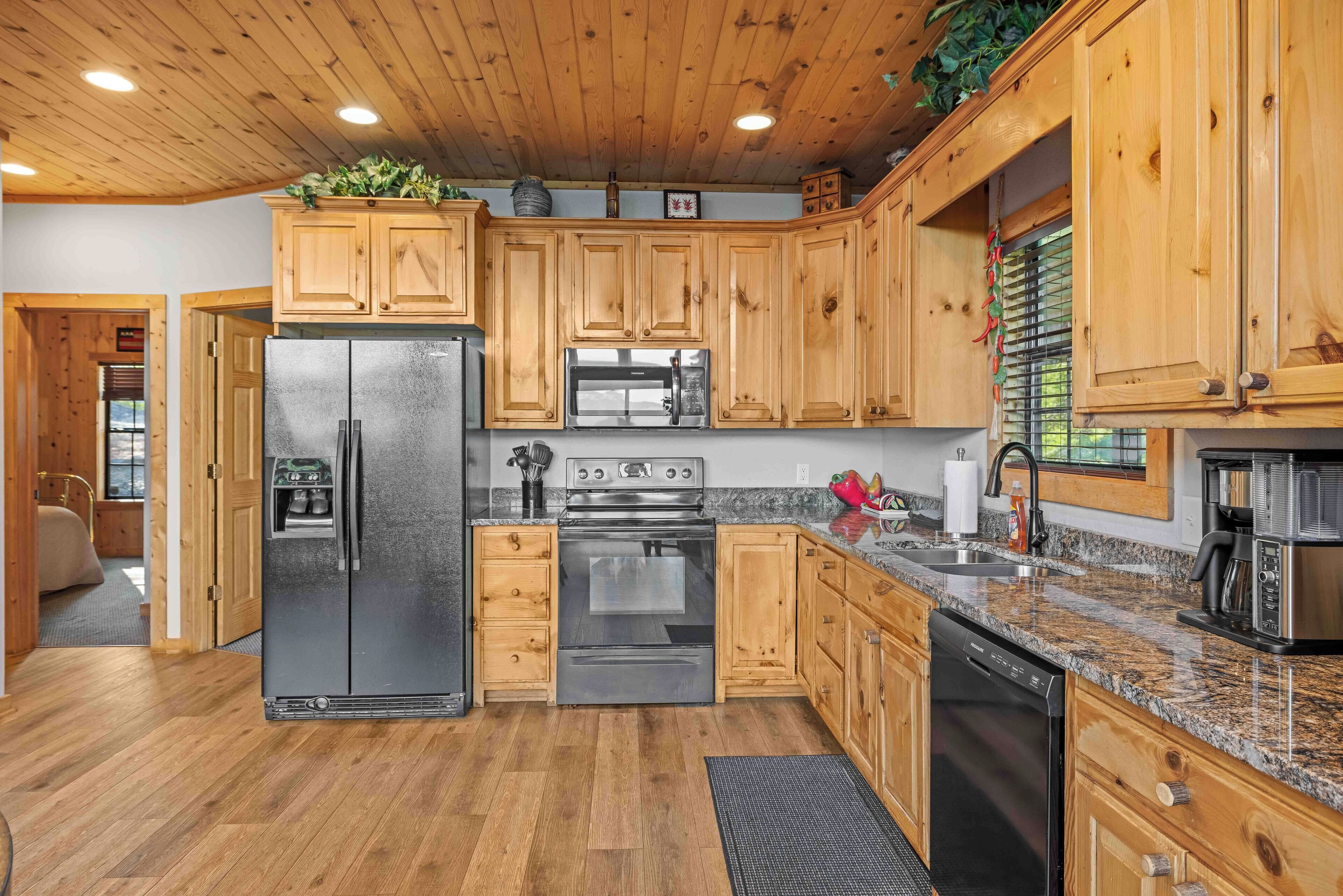 Una cocina moderna con armarios de madera, electrodomésticos de acero inoxidable, encimeras de granito y techo de madera.