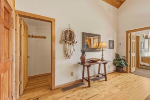 A wooden-floored hallway with a coat rack, a dreamcatcher, a mirror, and a small table with a vase and a lamp. - Yonah Vista - Luxury Couples Cabin (Cleveland)