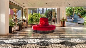 A lobby with a red circular seating area, large windows, and a tiled floor.