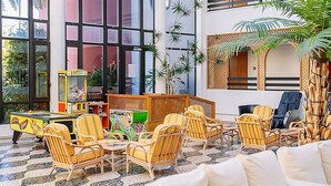 A room with large windows, wicker furniture, and a small table with a toy.