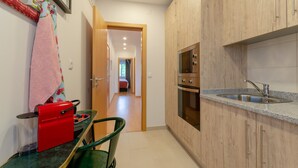 A compact kitchen with wooden cabinets, a stainless steel sink, and a built-in oven. - Setubal Boutique Apartment II by Homing (Setubal)