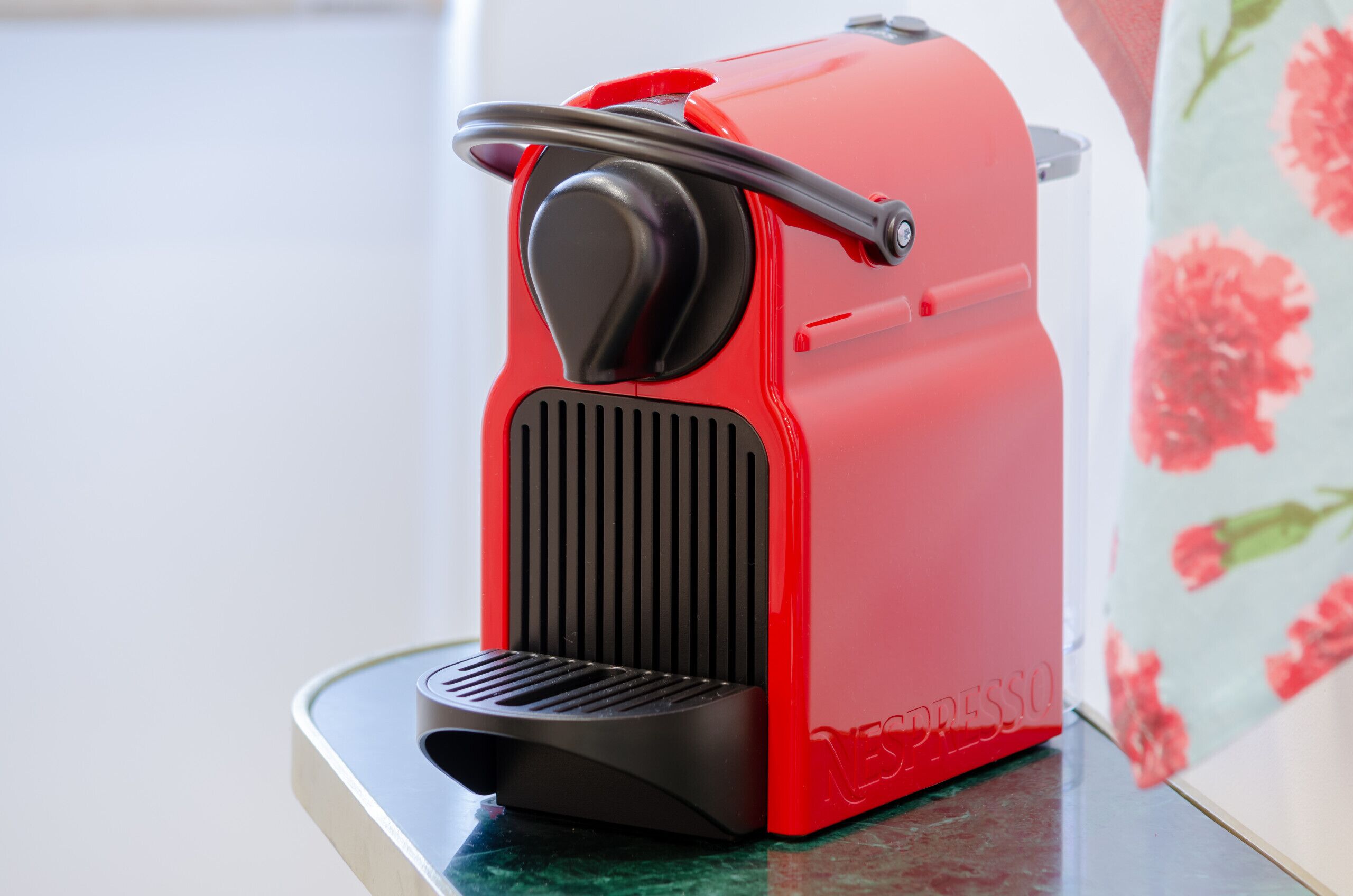 Una máquina de espresso roja con panel de control negro y un asa en la parte superior.