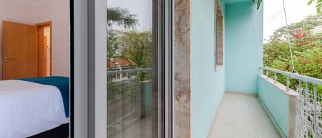 A bedroom with a bed, a sliding glass door leading to a balcony with a railing.