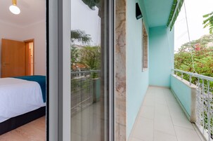Un dormitorio con cama, puerta de vidrio corrediza que da a un balcón con barandilla.