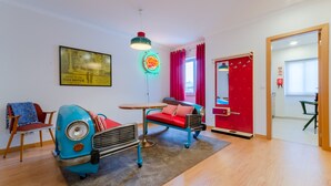 A modern living room with a vintage blue car, a red sofa, and a neon sign. - Setubal Boutique Apartment II by Homing (Setubal)