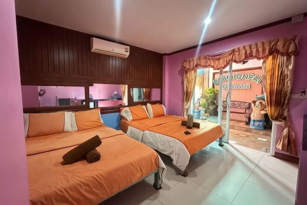 A hotel room with two beds, a window, an air conditioning unit, and a view of the beach.