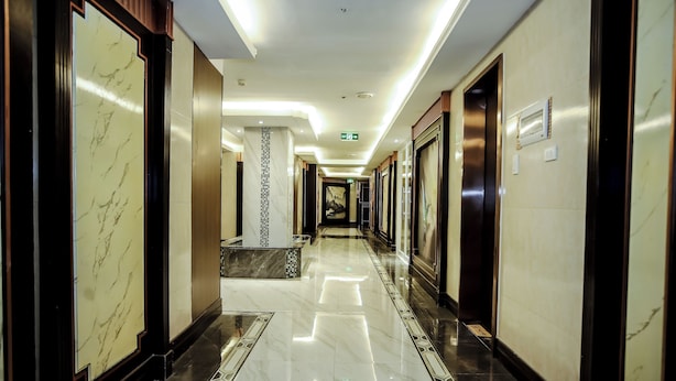 A long, well-lit hallway with marble floors and walls, leading to elevators and a central area with a marble column. - Underskies Spa and Hotel (Parañaque)