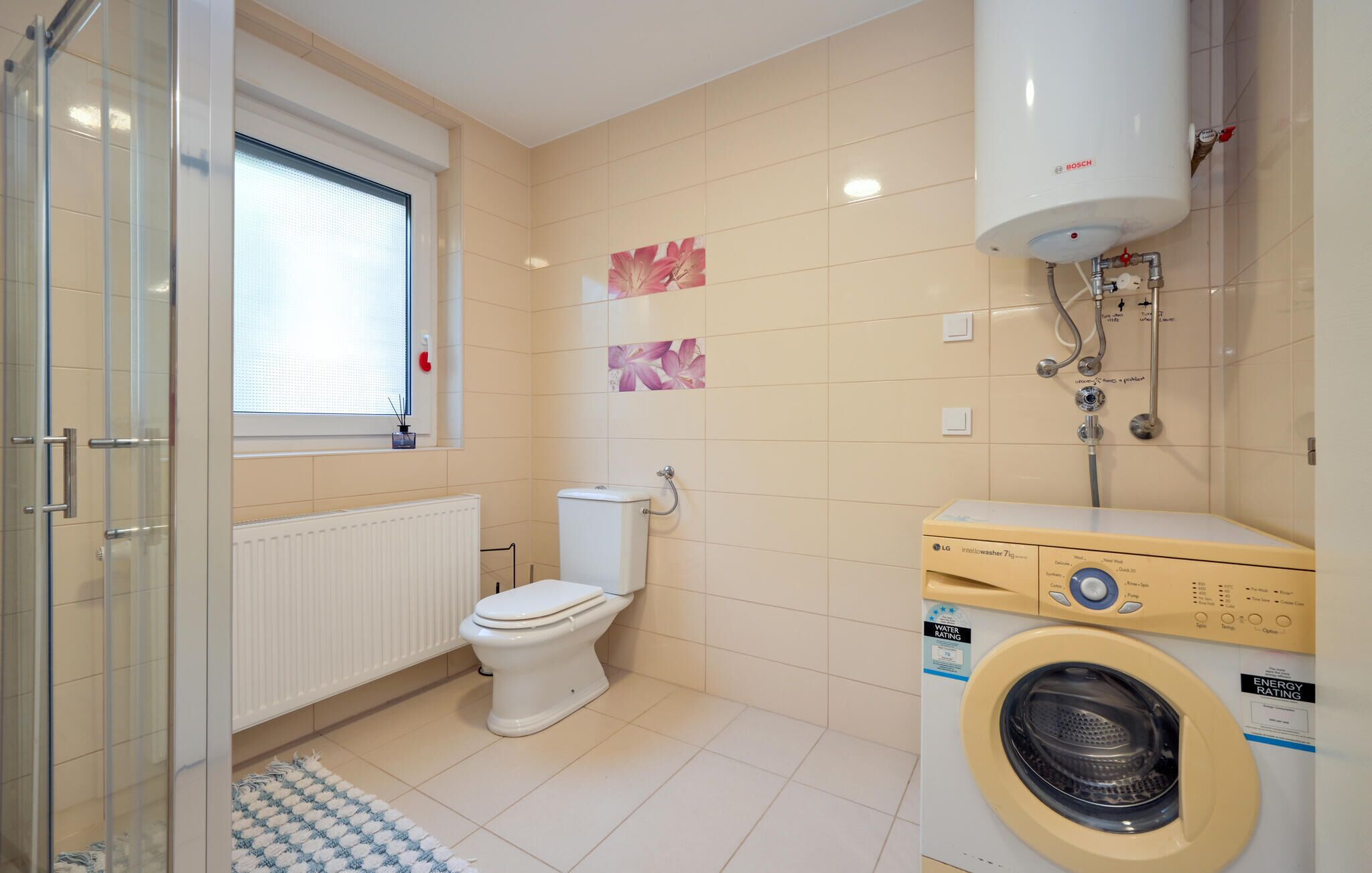 Un baño moderno con inodoro, lavadora y calentador de agua Bosch.