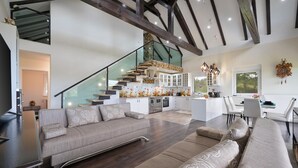 Een moderne woonkamer met een grote bank, een eethoek en een keuken met een centraal kookeiland.