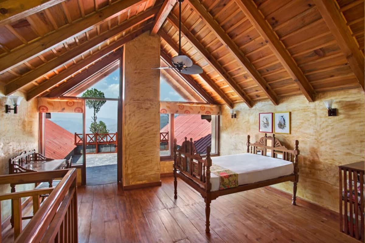 Um quarto espaçoso no sótão, com teto de madeira, uma cama, uma escrivaninha e vista para o exterior.