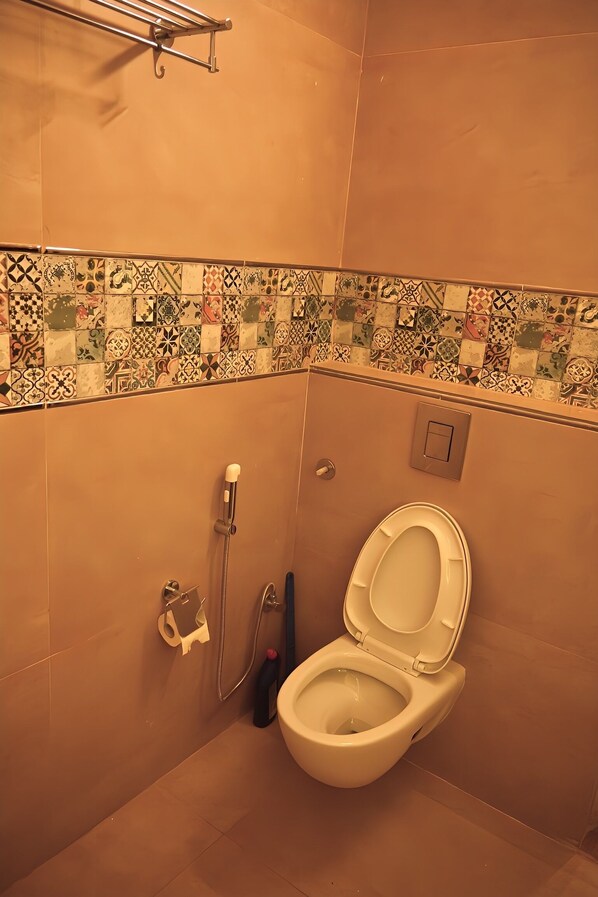 A small bathroom with a toilet, a shower, and a towel rack.