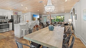 A spacious kitchen with modern appliances, a dining area with a large wooden table, and a chandelier. - "3 By The Sea" | Large Pool, 6 Bikes & 30A Charm, Steps to Beach Access (Santa Rosa Beach)