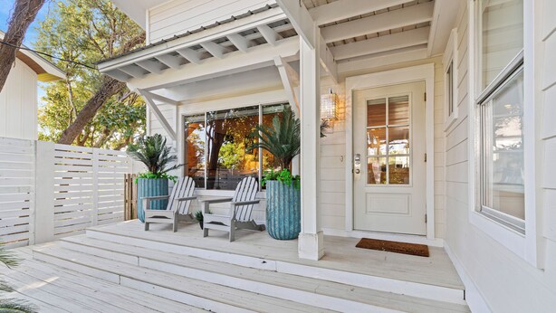 A covered porch with white wooden steps, two chairs, and two large planters. - "3 By The Sea" | Large Pool, 6 Bikes & 30A Charm, Steps to Beach Access (Santa Rosa Beach)