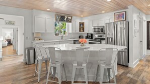 A modern kitchen with white cabinetry, stainless steel appliances, and a central island with bar stools. - "3 By The Sea" | Large Pool, 6 Bikes & 30A Charm, Steps to Beach Access (Santa Rosa Beach)