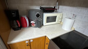 A kitchen with wooden cabinets, a microwave, a coffee maker, and a gas stove. - Chania City Center Apartment With Balcony & Central Aircon (Chania)