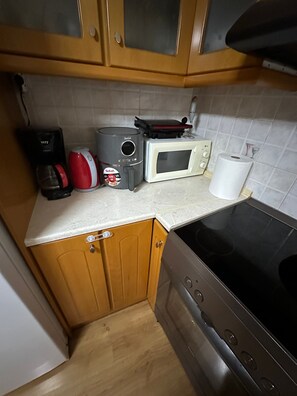 Una cocina con gabinetes de madera, un microondas, una cafetera y una estufa a gas.