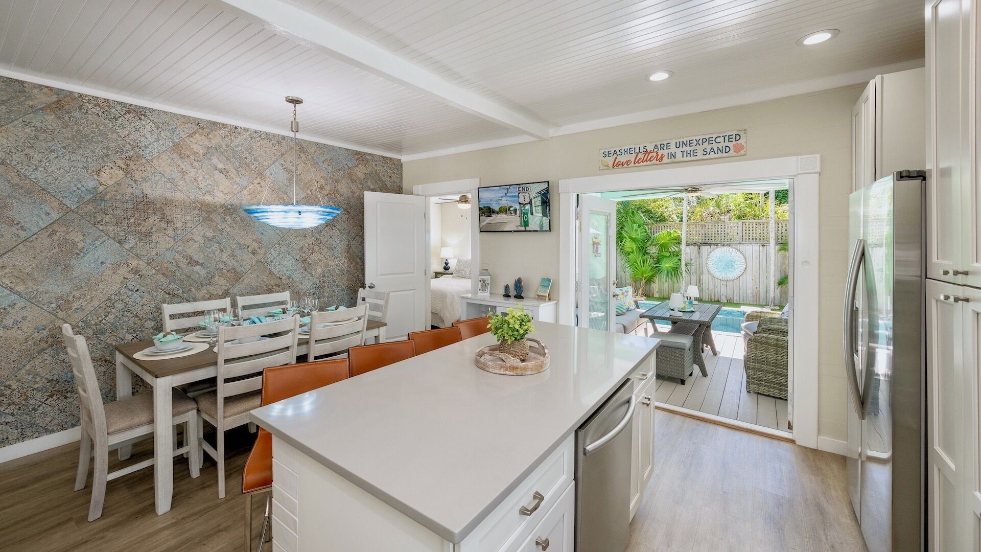 A modern kitchen with a central island, dining area, and a view of the backyard.