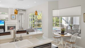 A modern kitchen with a built-in oven, a large window overlooking a pool, and a dining area with a table and chairs.