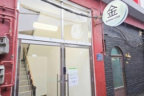 A building entrance with a glass door, a sign with Chinese characters, and a staircase leading inside. - Kumho Ryokan for Female Travelers – Near Dongdaemun (Seoul)