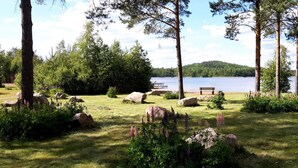 Ein Park am Seeufer mit einer Bank, Steinen und Bäumen.