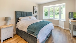 A bedroom with a bed, bedside tables, a TV, and a window with a view.