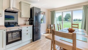 A modern kitchen with an oven, a refrigerator, and a dining area with a table and chairs.