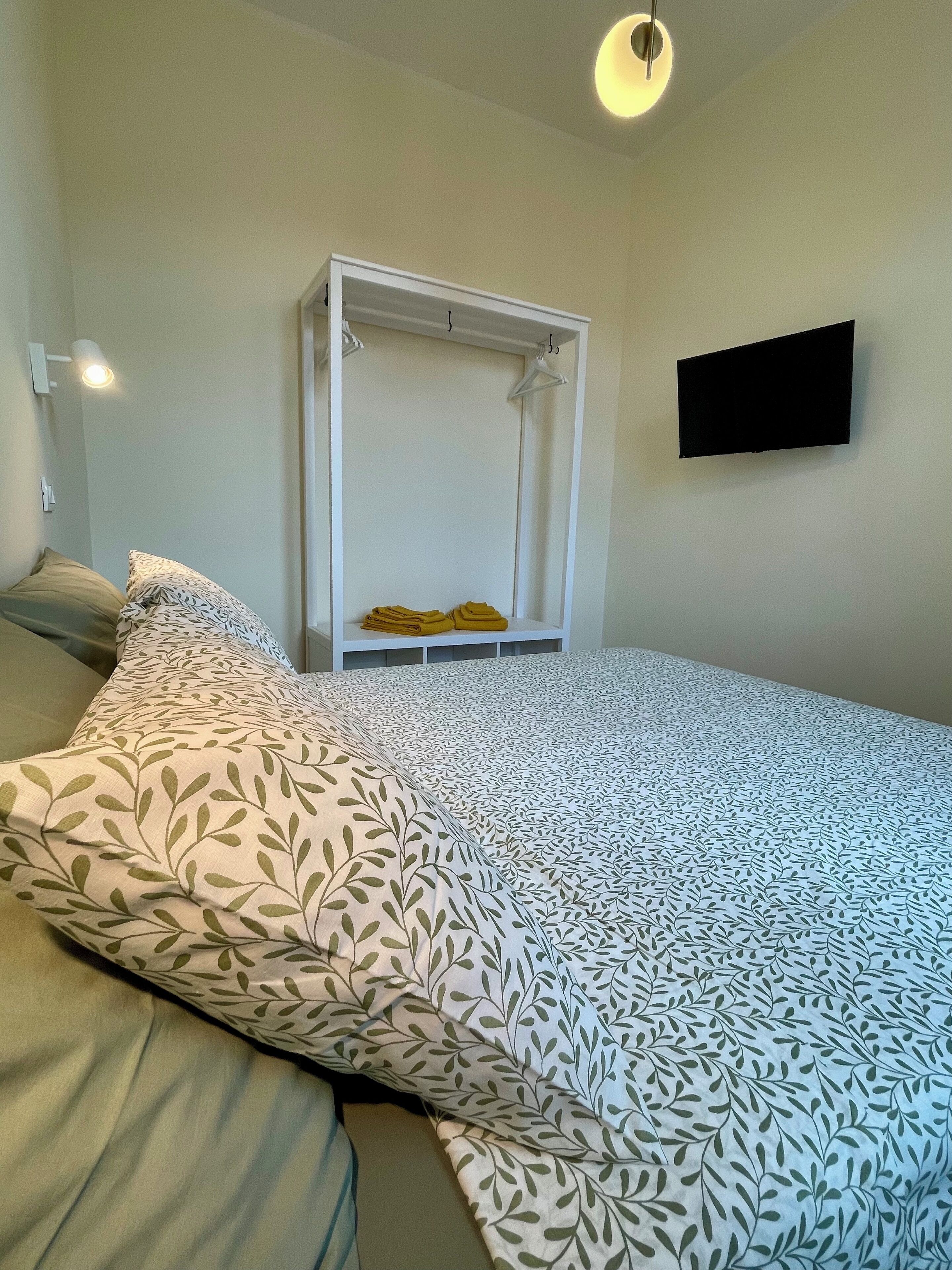 Ein Schlafzimmer mit Bett, Hängesessel, Fernseher und Nachttischlampe.