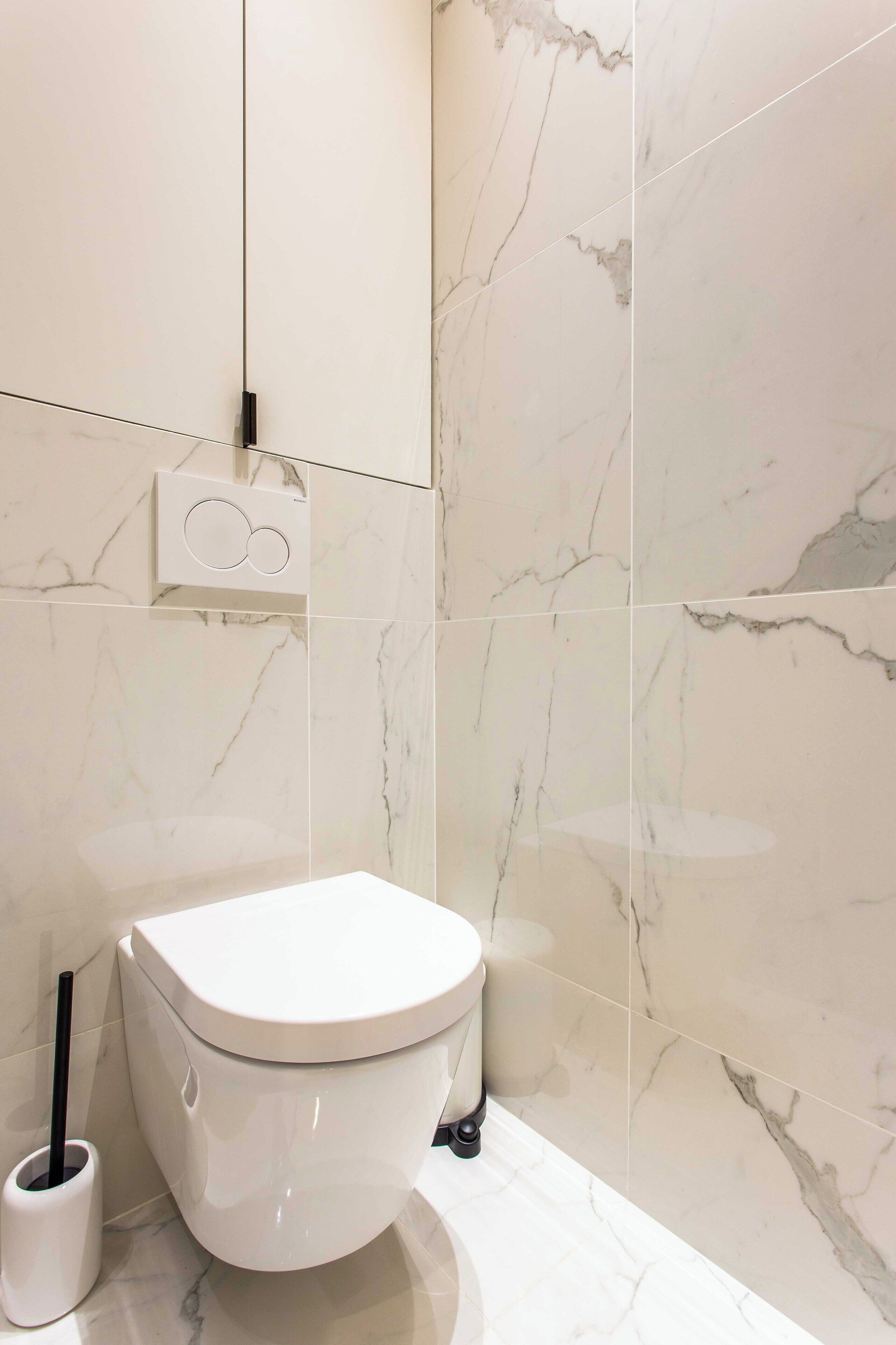 A modern bathroom with a toilet, a bidet, and a marble wall.