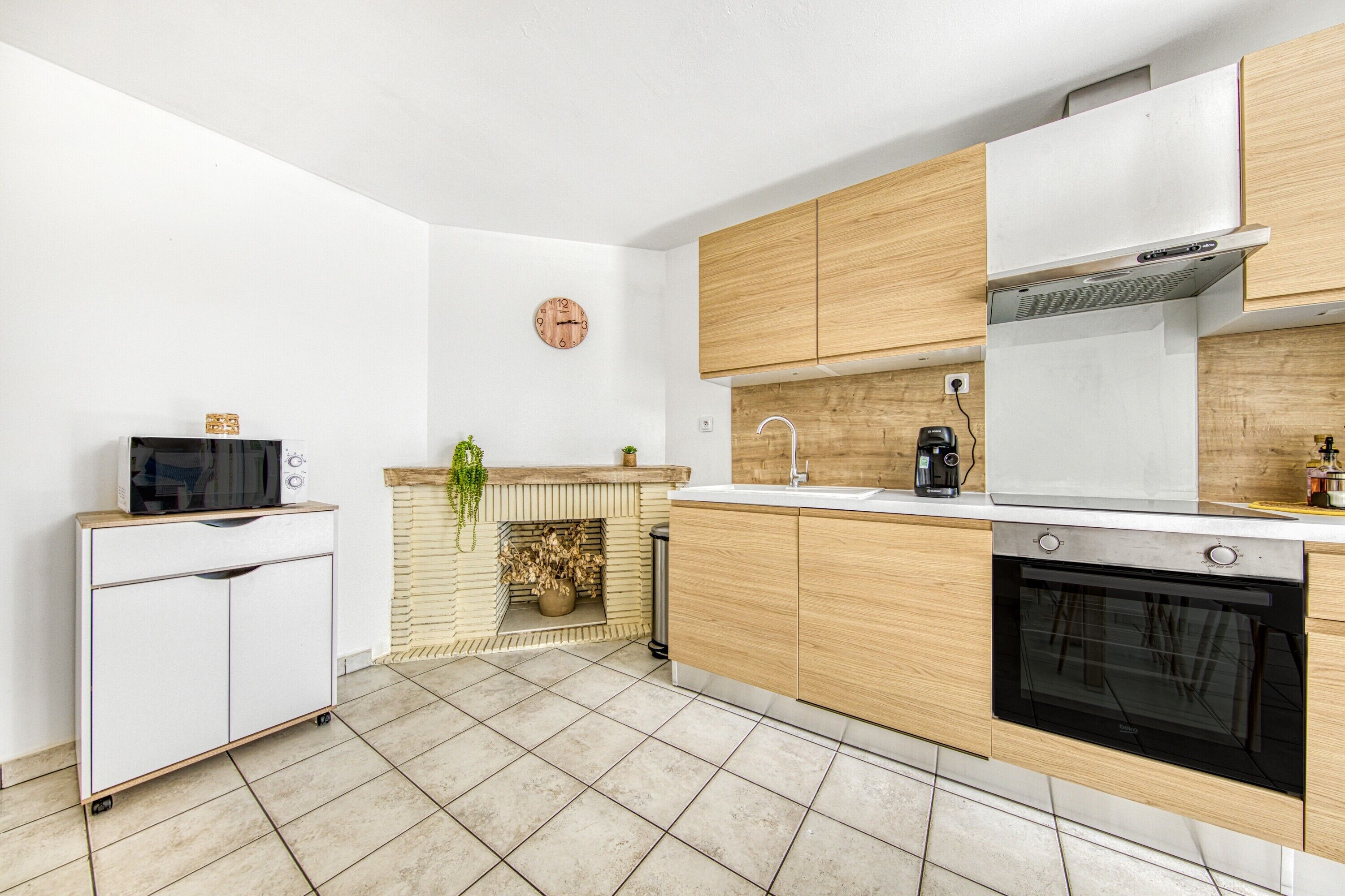 Une cuisine moderne équipée d’un four à micro-ondes, d’un four, d’un évier et de meubles de rangement en bois.