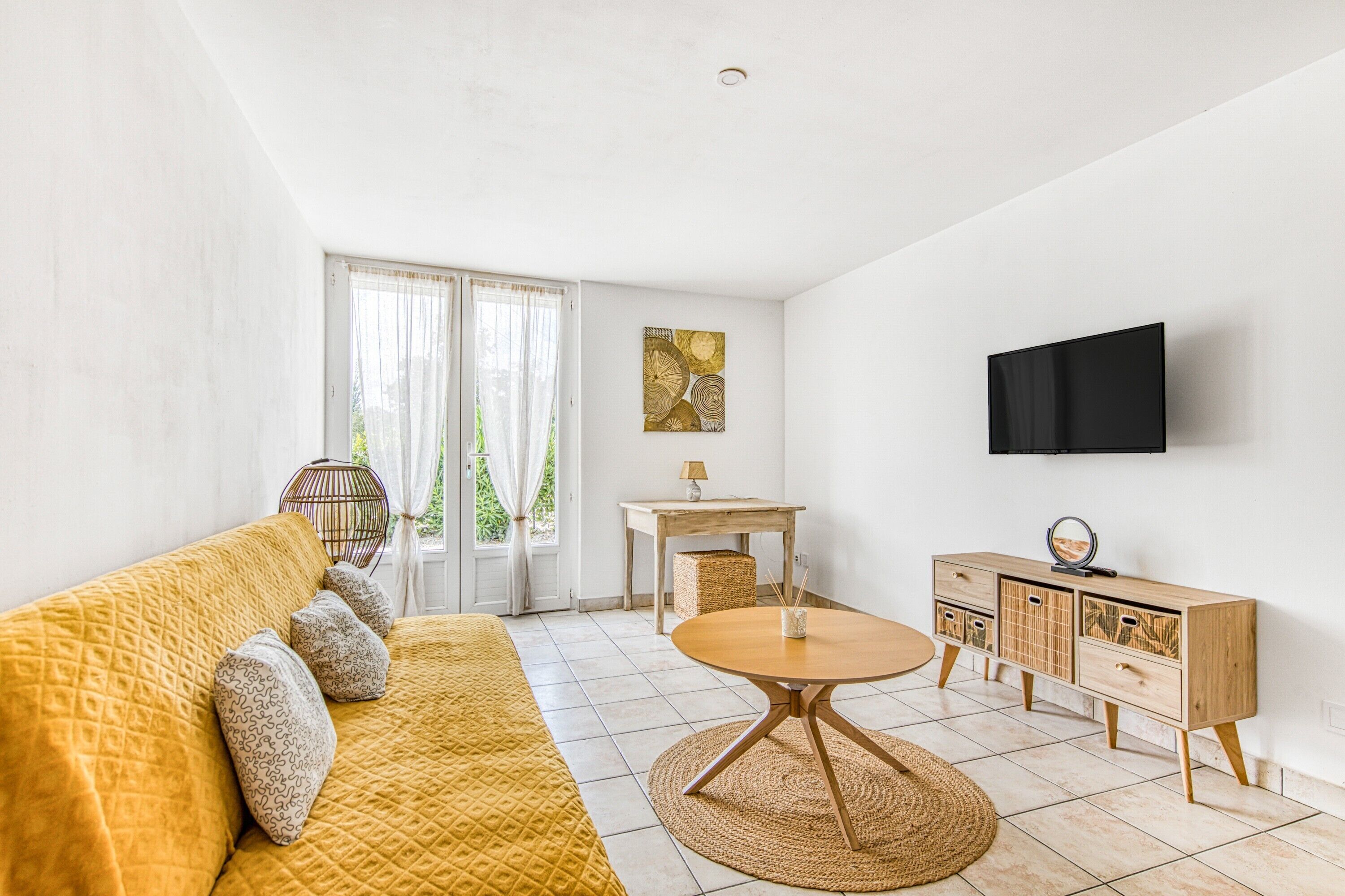 Een moderne woonkamer met een bank, een ronde tafel, een televisie en een houten kast.