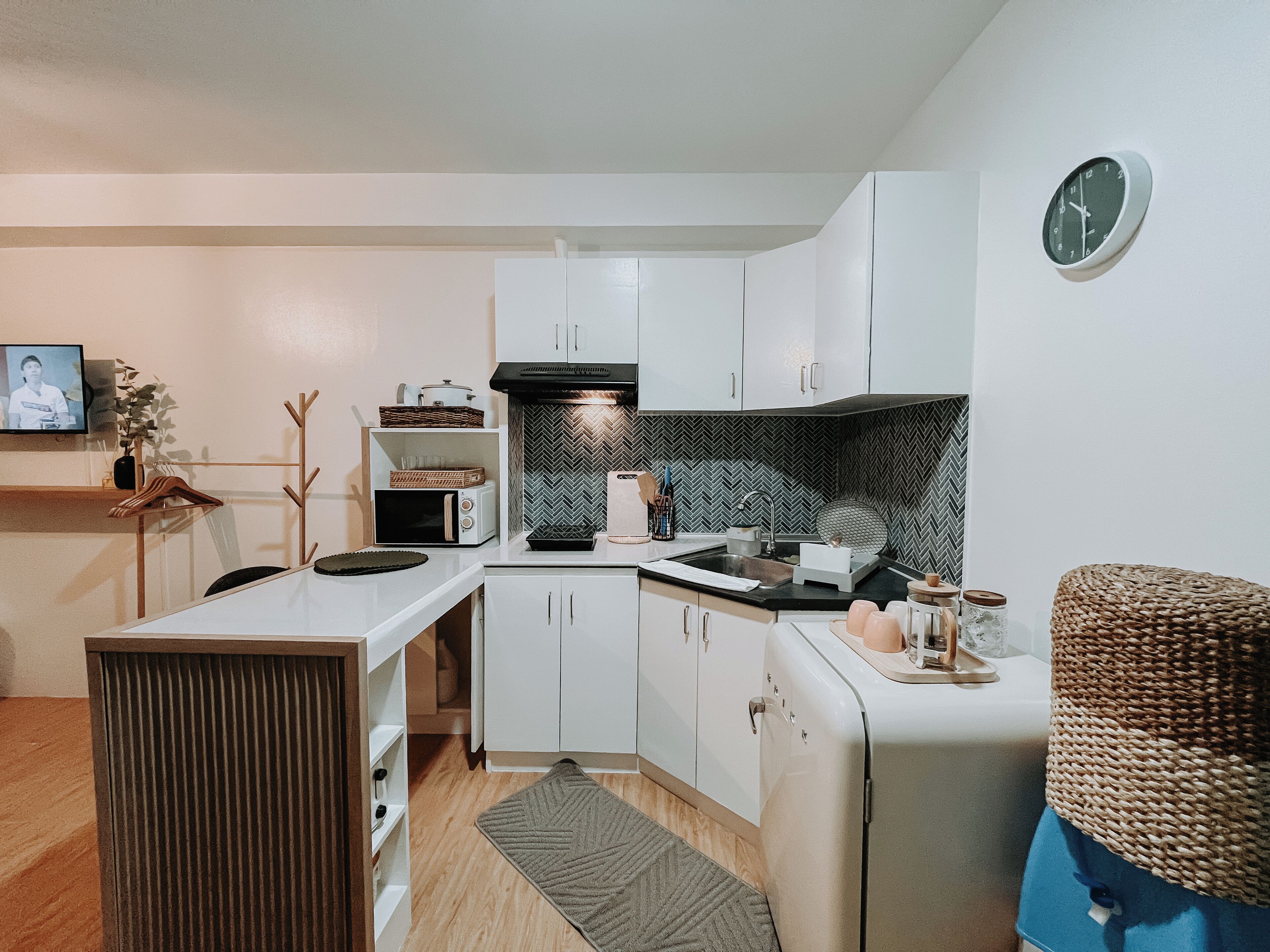 Una cocina compacta con alacenas blancas, un microondas, un tostador y un lavabo.