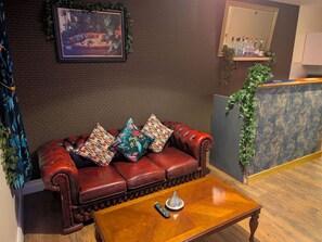 A room with a leather sofa, a wooden coffee table, a framed picture on the wall, a mirror, and a bar area with bottles. - Benny's Hideout - City Centre - Parking - 2BR (Belfast)
