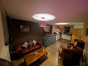 A living room with a sofa, armchairs, a coffee table, and a kitchen area in the background. - Benny's Hideout - City Centre - Parking - 2BR (Belfast)