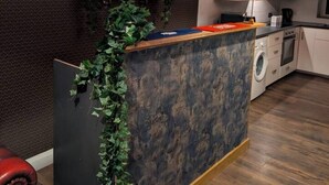 Una cocina moderna con lavadora incorporada, encimera de madera y un espejo arriba.