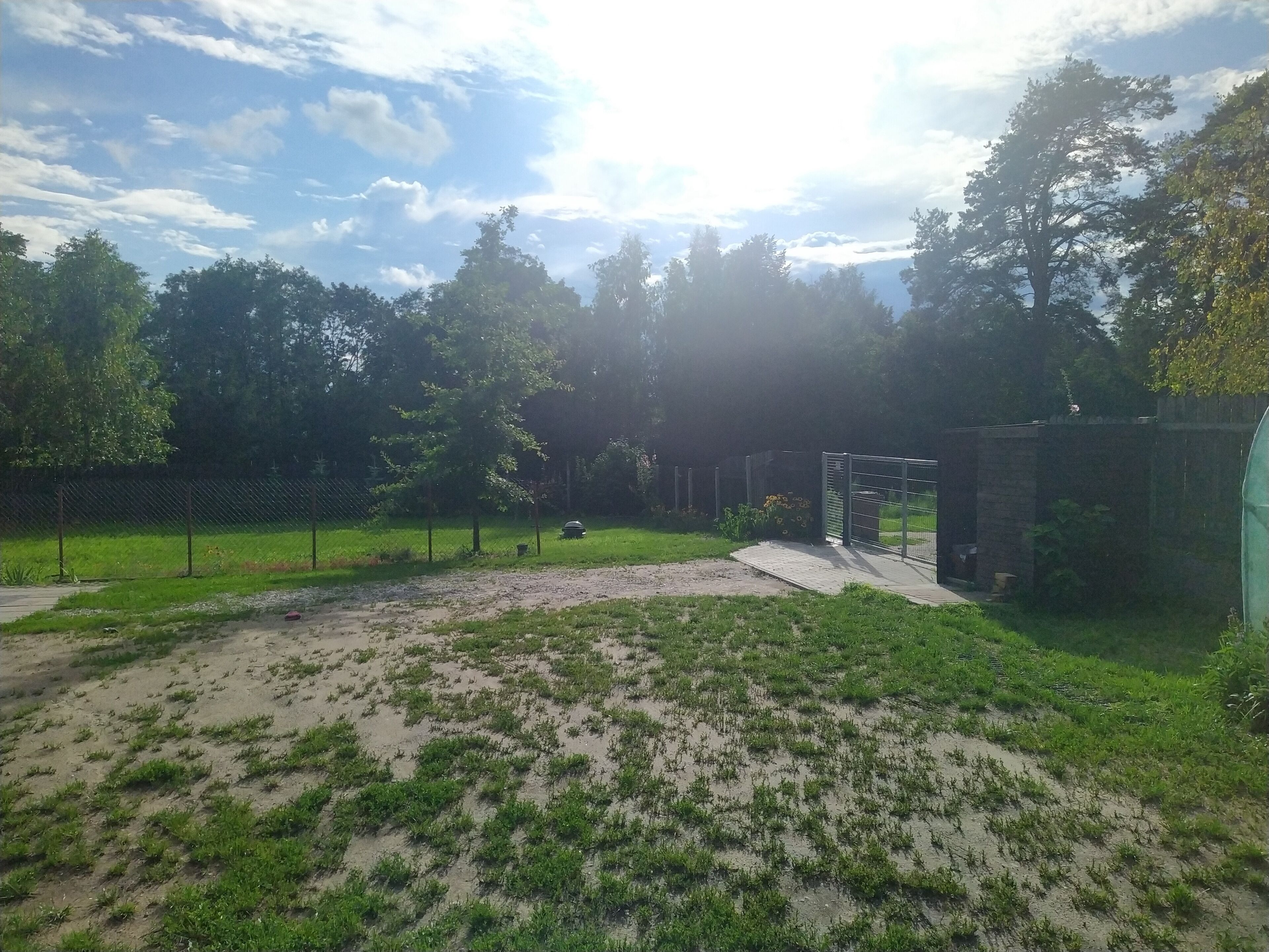A fenced outdoor area with a dirt path and sparse grass.