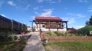 A two-story building with a red roof, a wooden deck, and a brick pathway leading to the entrance.