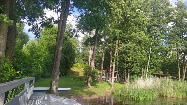 A wooden deck leading to a pond surrounded by trees.
