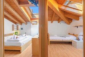 A room with two beds, wooden beams, a skylight, and a small bedside table with a lamp. - Torbole On the Moon (Nago-Torbole)