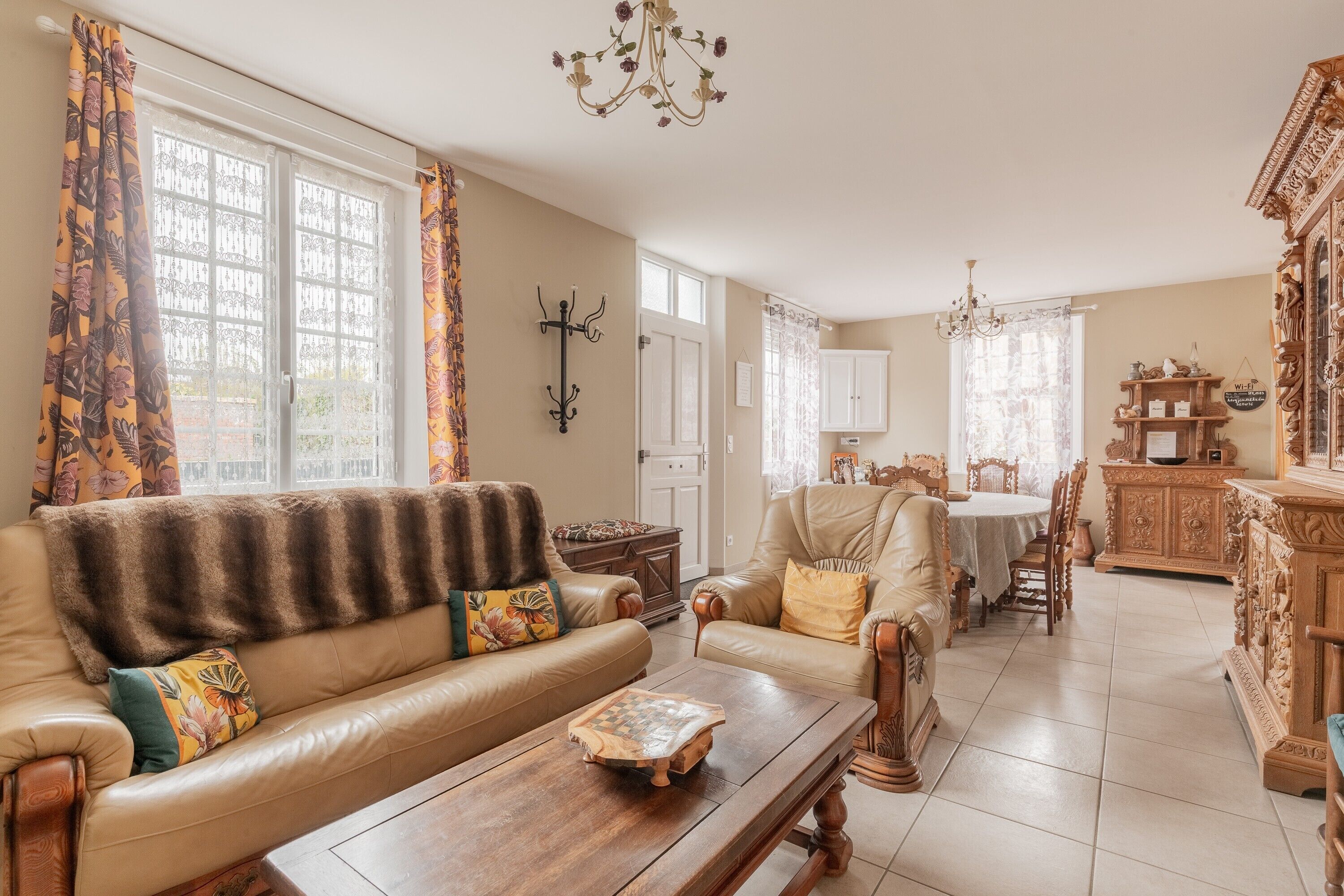 Ein Wohnzimmer mit Sofa, Sesseln, Couchtisch und Essbereich mit Tisch und Stühlen.