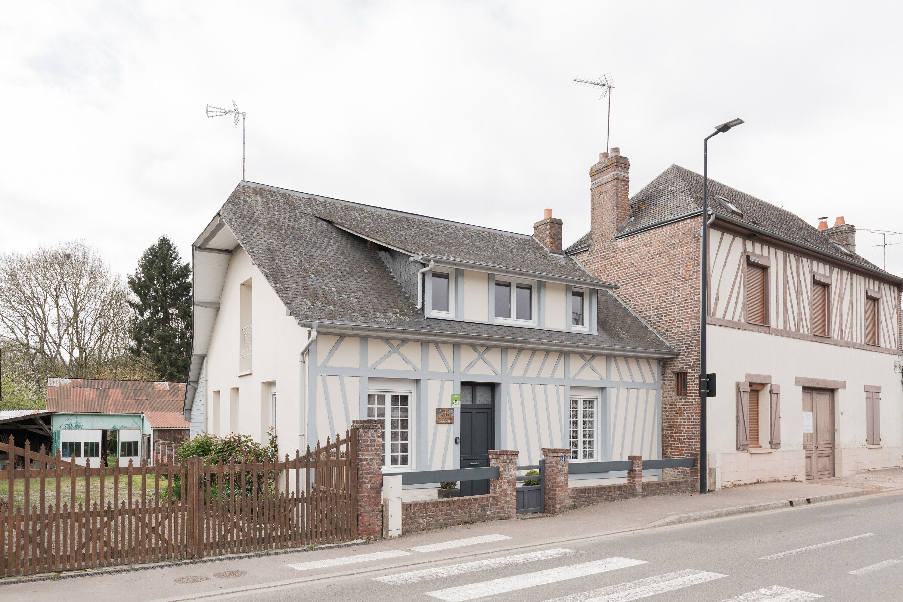 A traditional half-timbered house with a pitched roof, a gated entrance, and a visible chimney.