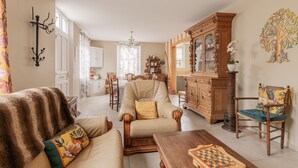 A living room with a sofa, armchair, wooden coffee table, and a chessboard.